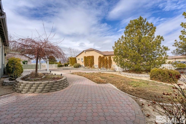 view of community with decorative driveway and fence