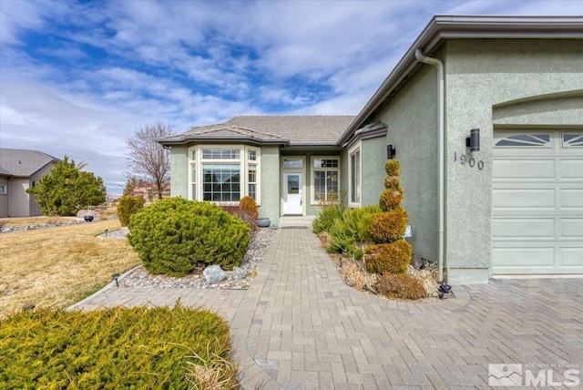 doorway to property with an attached garage and stucco siding