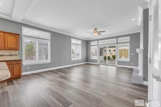 unfurnished living room featuring light wood-type flooring, ceiling fan, baseboards, and ornamental molding