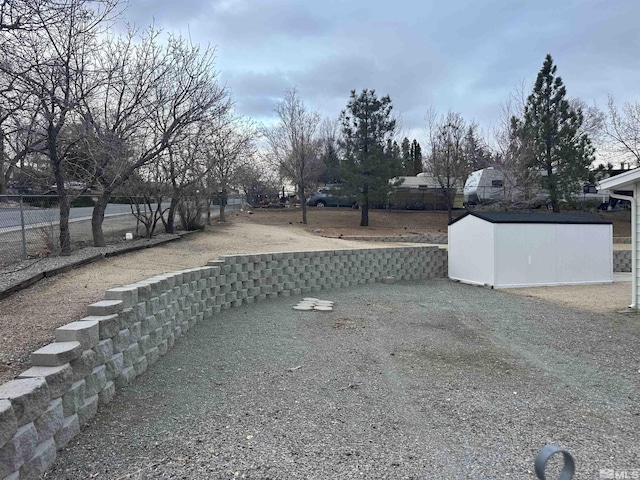 view of yard featuring a storage unit, fence, and an outdoor structure