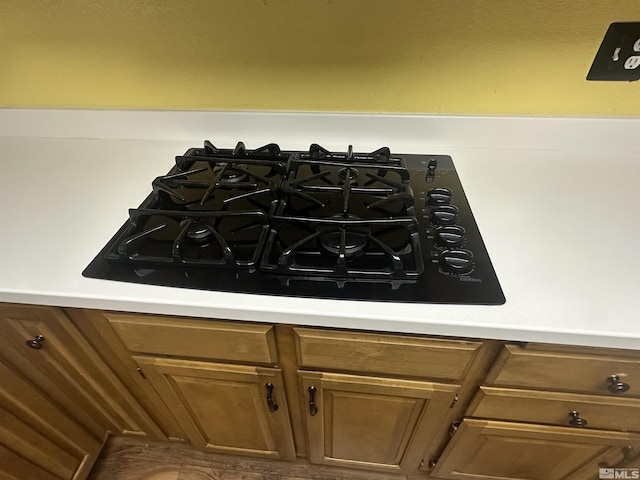 room details featuring light countertops, black gas stovetop, and brown cabinetry