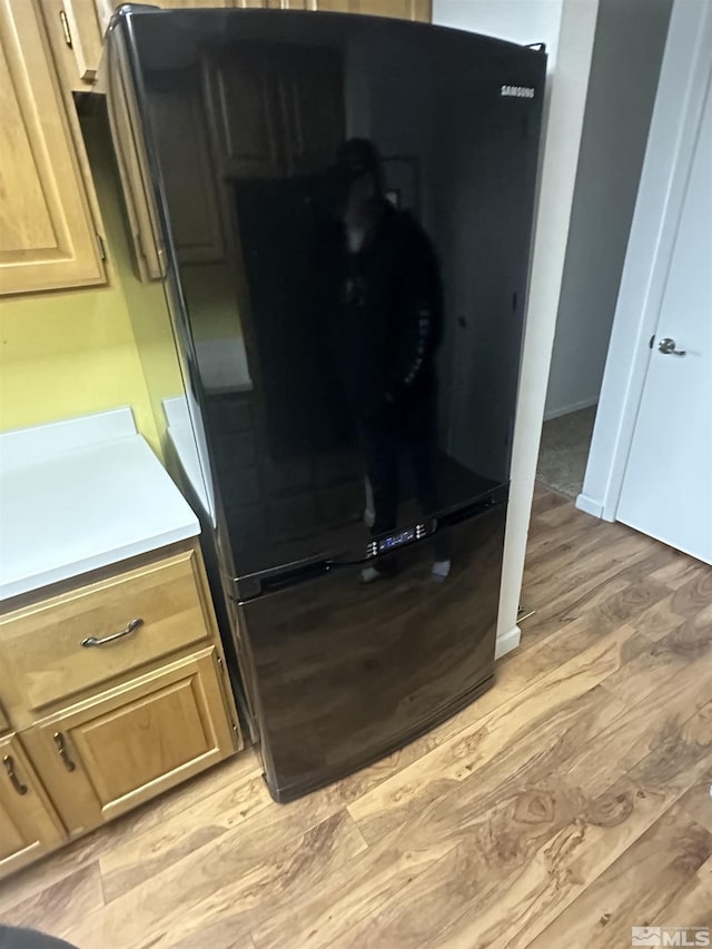 kitchen featuring light wood-type flooring, light brown cabinets, light countertops, and freestanding refrigerator