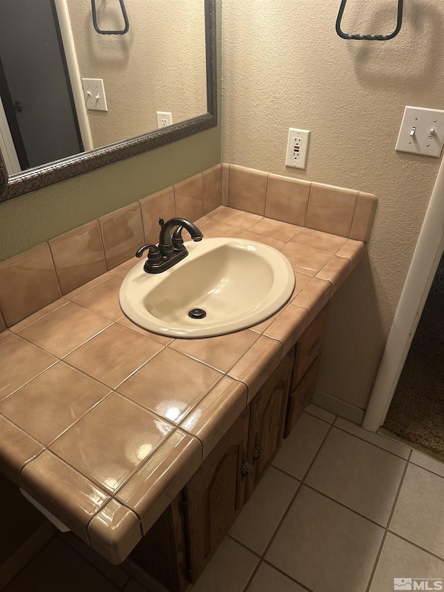 bathroom with a textured wall, vanity, and tile patterned floors