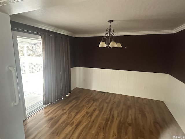 unfurnished dining area featuring dark wood-type flooring, a chandelier, visible vents, and ornamental molding