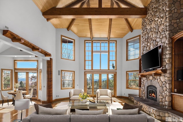 living area featuring high vaulted ceiling, wood ceiling, a fireplace, and wood finished floors