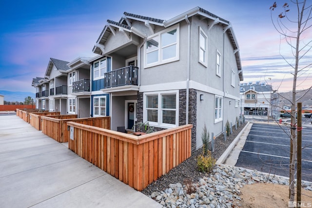 property exterior at dusk featuring stone siding and stucco siding