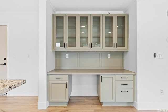 bar with light wood-style floors, crown molding, built in desk, and baseboards