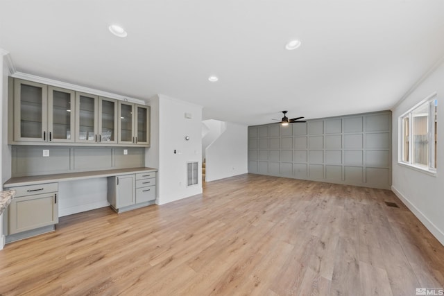 unfurnished living room featuring light wood-style flooring, visible vents, and built in desk