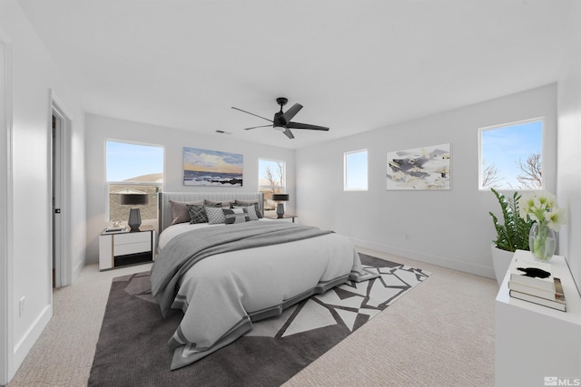 bedroom featuring light carpet, a ceiling fan, and baseboards