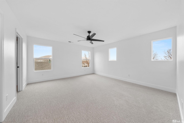 spare room featuring light carpet, ceiling fan, and baseboards