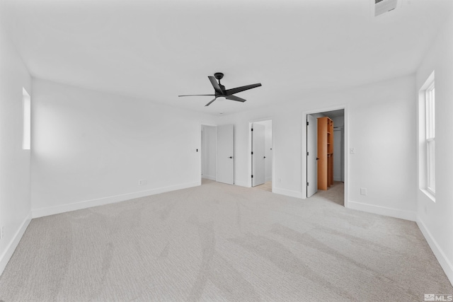 unfurnished bedroom featuring light colored carpet, visible vents, a spacious closet, and baseboards