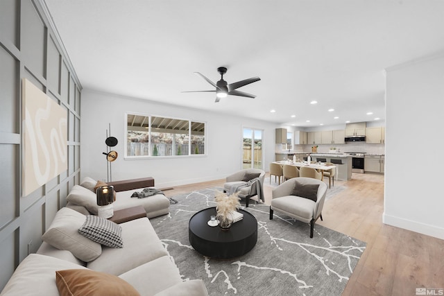 living room with light wood-style flooring, baseboards, a ceiling fan, and recessed lighting