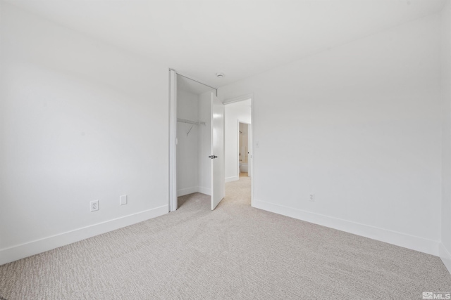 unfurnished bedroom with light carpet, baseboards, and a closet