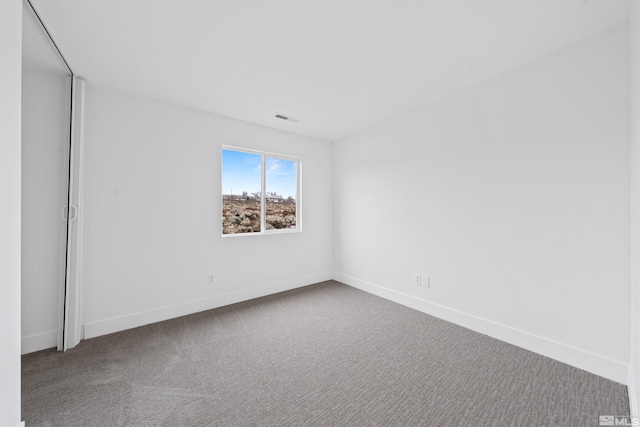 unfurnished room with carpet, visible vents, and baseboards