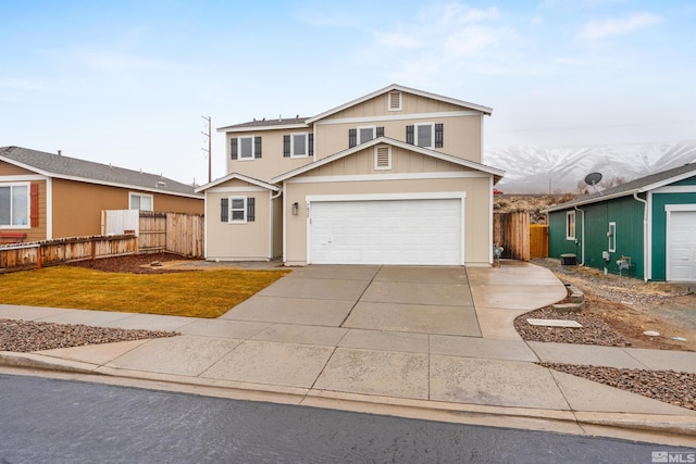 traditional-style home featuring a garage, concrete driveway, and fence