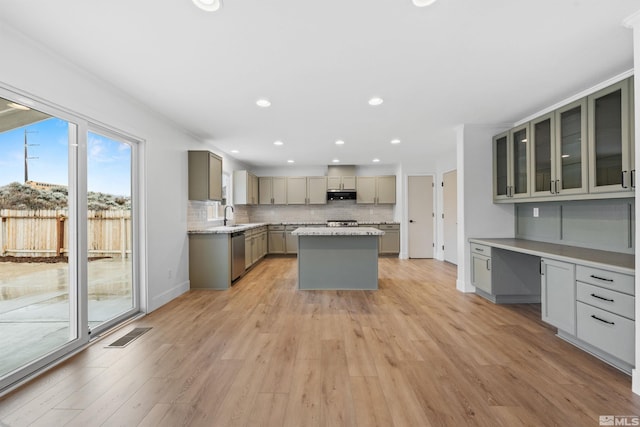 kitchen with appliances with stainless steel finishes, backsplash, gray cabinets, and built in study area