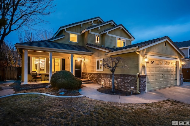 craftsman-style house featuring a porch, concrete driveway, a tile roof, and an attached garage