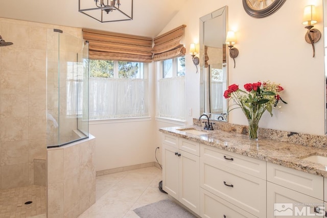 bathroom featuring tile patterned floors, double vanity, a sink, and a walk in shower