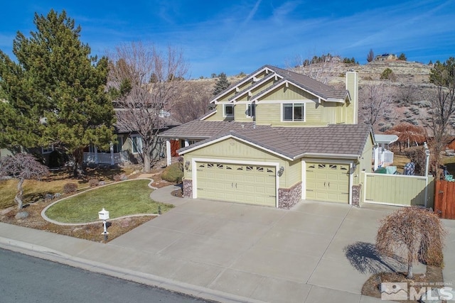 craftsman inspired home with a chimney, a front yard, fence, stone siding, and driveway