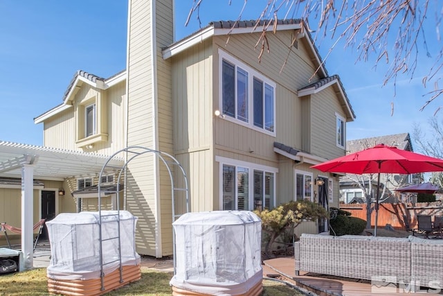 back of property featuring a chimney and a pergola