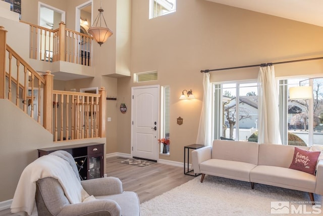 living room featuring stairway, wood finished floors, a towering ceiling, and baseboards