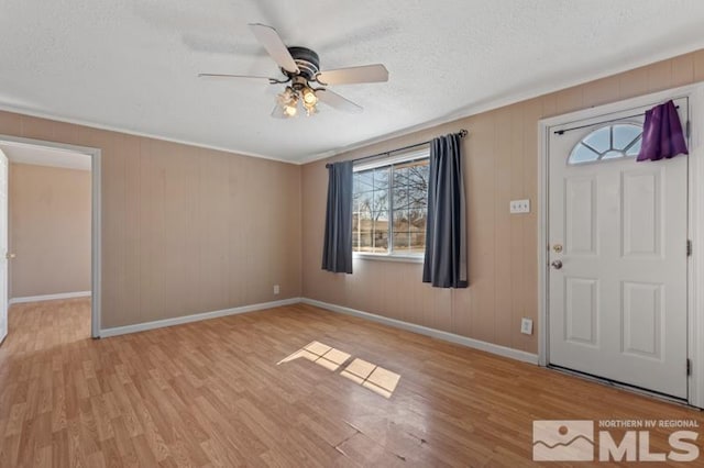 foyer entrance featuring light wood finished floors, baseboards, a ceiling fan, and a textured ceiling