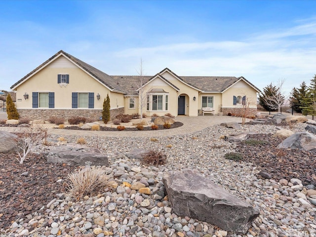 ranch-style house featuring stone siding and stucco siding