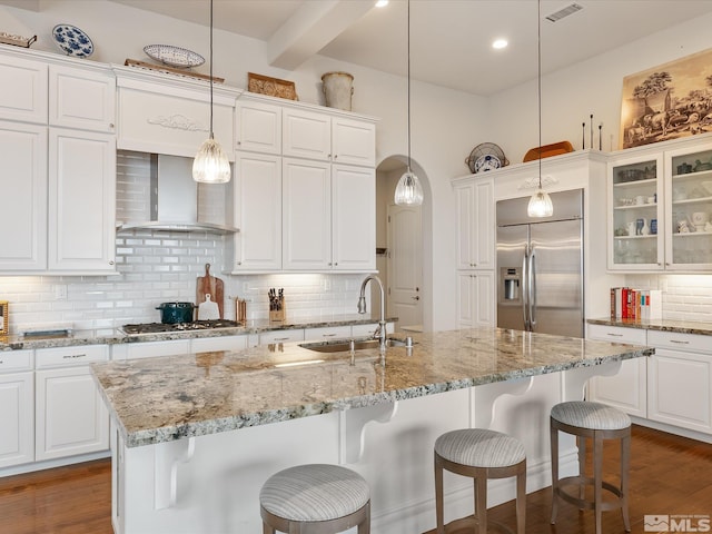 kitchen featuring white cabinets, dark wood-type flooring, stainless steel appliances, wall chimney range hood, and a sink