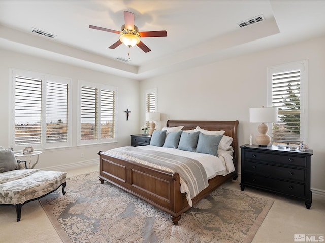 bedroom with a tray ceiling and visible vents