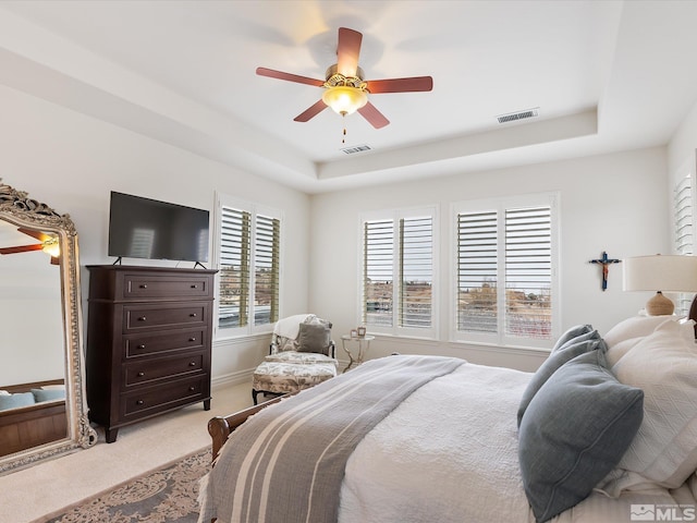 bedroom featuring light carpet, ceiling fan, a raised ceiling, and visible vents