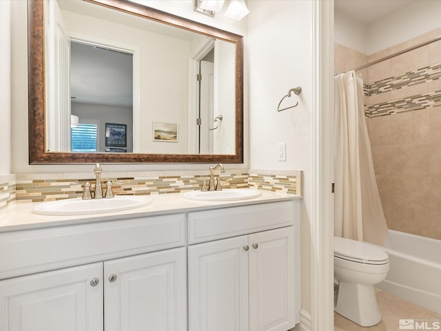 bathroom with double vanity, tasteful backsplash, a sink, and toilet