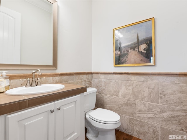 bathroom featuring a wainscoted wall, vanity, toilet, and tile walls