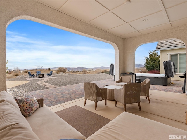 view of patio / terrace featuring a hot tub, a mountain view, and an outdoor hangout area