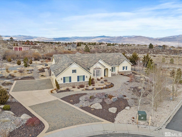 view of front facade featuring decorative driveway, a mountain view, and stucco siding