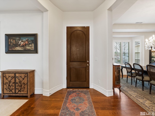 entrance foyer featuring baseboards, dark wood-style flooring, visible vents, and an inviting chandelier