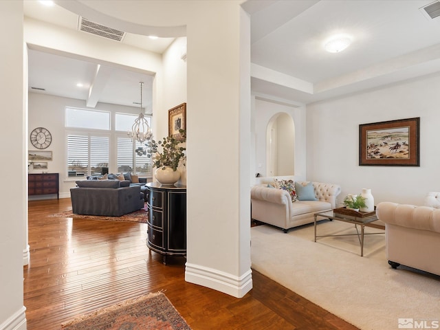 living room with visible vents, arched walkways, and dark wood-style flooring