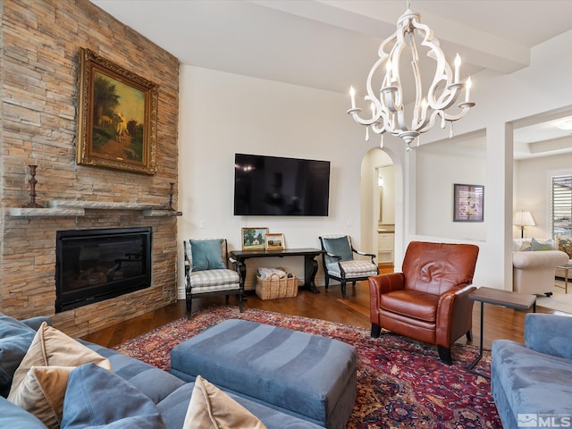 living room with beam ceiling, a fireplace, arched walkways, and wood finished floors