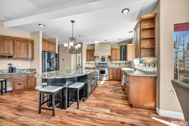 kitchen with range with two ovens, wall chimney exhaust hood, a breakfast bar area, open shelves, and black fridge