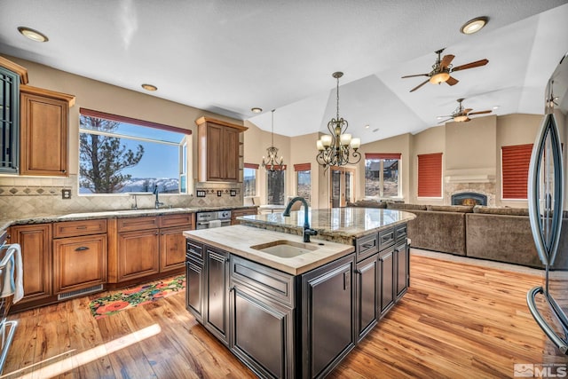 kitchen with a warm lit fireplace, a sink, decorative light fixtures, and light wood-style floors