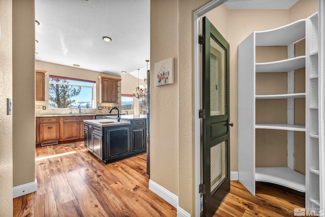 kitchen with brown cabinetry, baseboards, a textured wall, and light wood finished floors