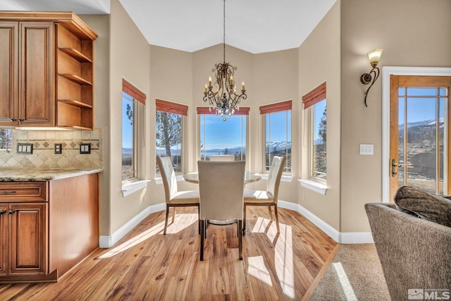 dining space featuring a healthy amount of sunlight, light wood-style flooring, baseboards, and an inviting chandelier