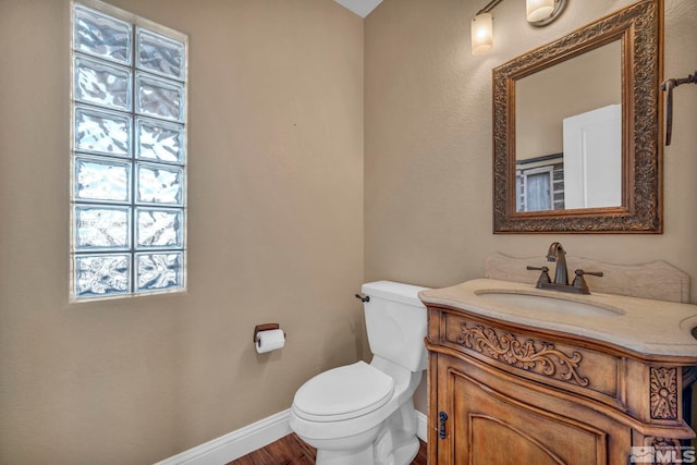 bathroom with toilet, plenty of natural light, vanity, and baseboards