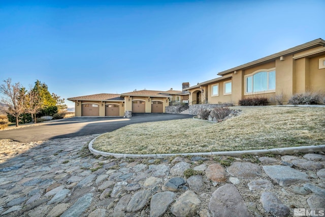 view of front facade with a garage, aphalt driveway, and stucco siding