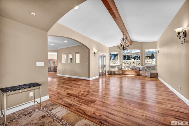 unfurnished living room with vaulted ceiling with beams, arched walkways, wood finished floors, and baseboards