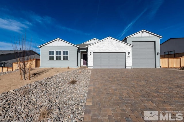 ranch-style home with decorative driveway, board and batten siding, an attached garage, and fence