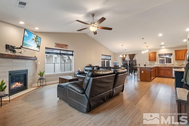 living area featuring lofted ceiling, light wood-type flooring, visible vents, and a tile fireplace