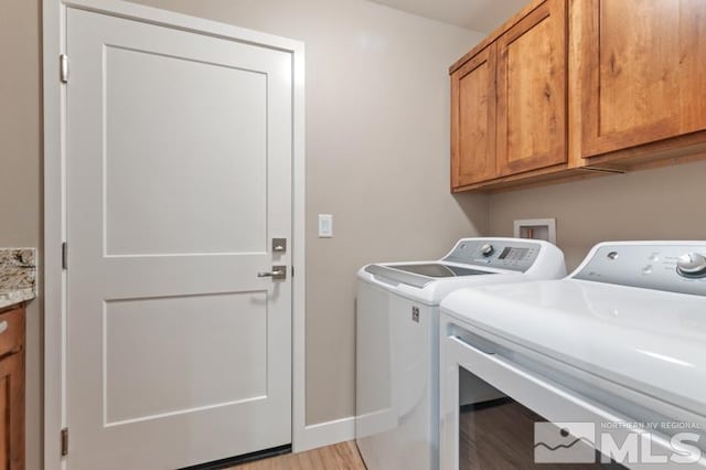 laundry room featuring baseboards, cabinet space, light wood-style floors, and independent washer and dryer