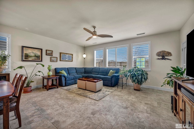 living area with baseboards, visible vents, and ceiling fan