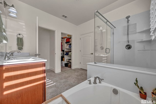 full bathroom with a stall shower, visible vents, a garden tub, a walk in closet, and vanity