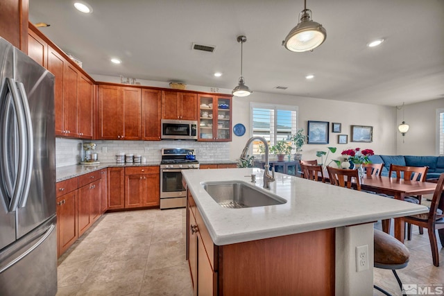 kitchen featuring a breakfast bar, a sink, visible vents, appliances with stainless steel finishes, and decorative backsplash